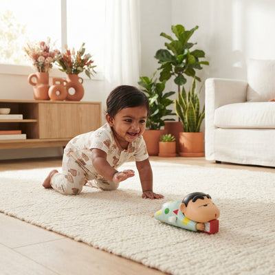 A South Asian baby crawling toward a Shinchan toy on a cream-colored rug in a sunlit living room.